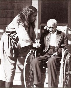 Paramahansa Yogananda with a man on a wheelchair.