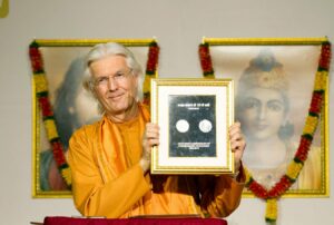 Swami Chidananda displays the newly released commemorative coin honouring.
